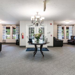 A spacious living room interior with a central table and chandelier.