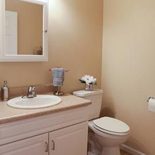 A clean and simple bathroom with a sink, mirror, and toilet.