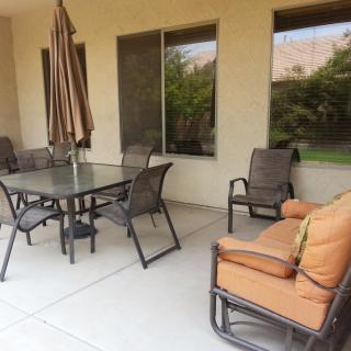 A cozy patio with a dining set and cushioned seating, perfect for outdoor gatherings.