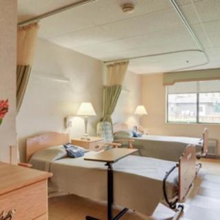 A hospital room with two beds, bedside tables, and curtain dividers.