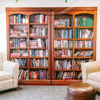 A cozy reading area featuring a large wooden bookshelf filled with books, flanked by comfortable chairs.