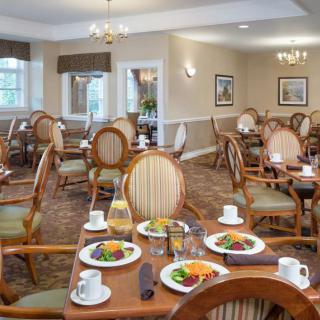 A well-arranged dining room with tables set for a meal, featuring elegant chairs and plates of food.
