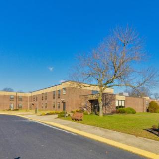 A modern school building surrounded by a clear blue sky and a well-kept lawn.