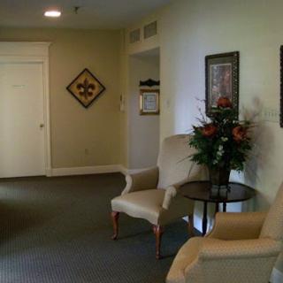 A cozy waiting area featuring comfortable chairs, decorative art on the walls, and a small table with flowers.