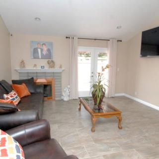 A cozy living room with a sofa, coffee table, and fireplace, featuring a television mounted on the wall.