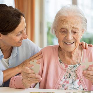 A caregiver provides support and companionship to an elderly woman.