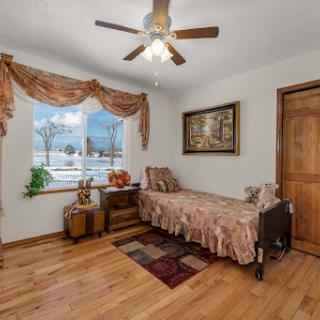 A cozy bedroom featuring warm wooden tones, decorative curtains, and a comfortable bed ideal for relaxation.