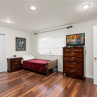 A neatly arranged bedroom with wooden flooring, featuring a single bed, a dresser, and a nightstand.