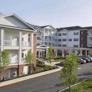 A suburban residential apartment building with a landscaped parking area.