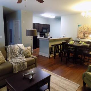 A cozy open-plan living area featuring a comfortable sofa, coffee table, and a dining area with bar stools overlooking the kitchen.