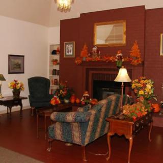 A cozy living room with autumn-themed decorations, featuring a fireplace and comfortable seating.