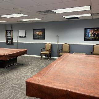 A spacious conference room with covered tables, chairs, and framed artwork on the walls.