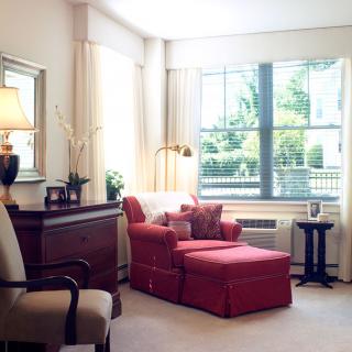 A cozy living room with a large window, showcasing a comfortable armchair and stylish decor.