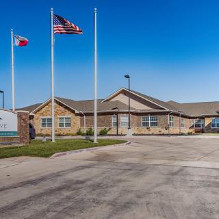 A one-story building with three flags in front, set against a clear blue sky.
