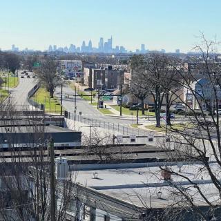 A view of a city skyline from a suburban neighborhood with roads, buildings, and trees.