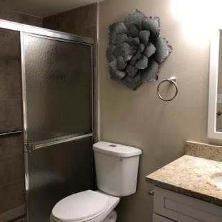 A modern bathroom featuring a shower, toilet, and decorative wall art.