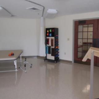 An empty rehabilitation room equipped with exercise tables and therapy equipment.