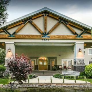 The front entrance of a building featuring prominent wood beams and well-maintained landscaping.