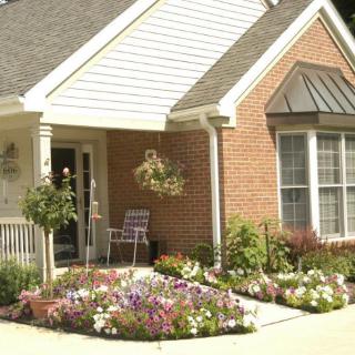 A charming brick house with a well-maintained garden full of colorful flowers.