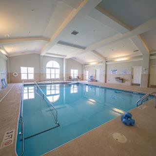 A spacious indoor swimming pool area with large windows and bright lighting.