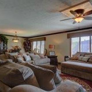 A cozy and well-decorated living room with plush seating, ceiling fan, and large windows.