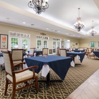 An elegant dining room with neatly arranged tables and chairs, adorned with chandeliers.