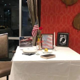 A restaurant table set as a memorial tribute with an American flag, POW/MIA symbol, and a single rose.