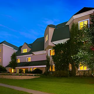 A well-lit hotel building with illuminated windows, surrounded by greenery at night.