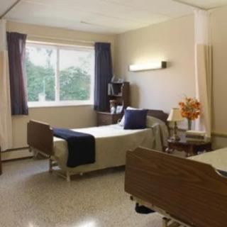 A clean and organized hospital room with two beds and a large window.