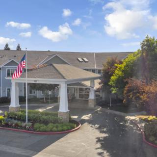 A building entrance with American flags, surrounded by trees and a clear sky.