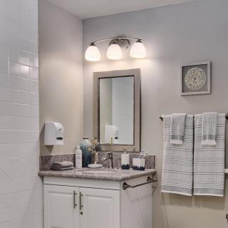 A clean and modern bathroom with a lighted vanity, mirror, and neatly arranged towels.