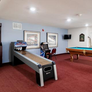 A game room featuring a shuffleboard table, pool table, and an arcade machine for entertainment.