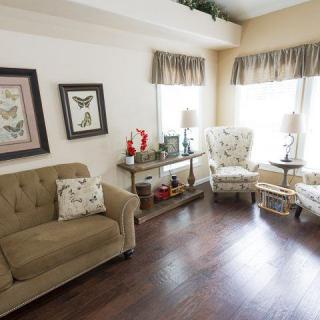 A cozy living room features a sofa, armchair, and decorative elements with ample natural light.