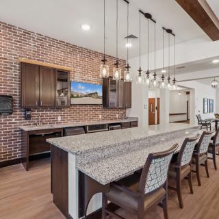 A modern kitchen with a brick accent wall, featuring an island counter and stylish pendant lighting.