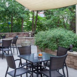 A tranquil outdoor patio with shaded seating surrounded by lush greenery.