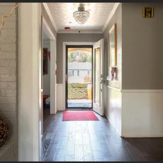 A bright hallway with a door leading outside, featuring a red mat and overhead light fixture.