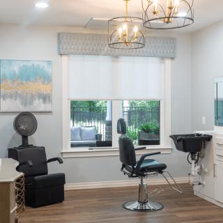A modern hair salon interior featuring styling chairs, hair dryers, and a wash basin.
