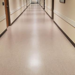 A long, well-lit hallway with smooth flooring and closed doors on either side.