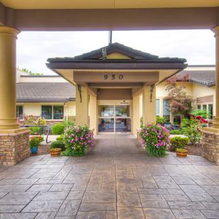 The entrance of a building with landscaped gardens and columns.