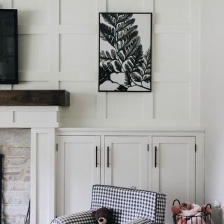 A cozy living room corner with a framed artwork above the fireplace and a patterned armchair.