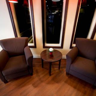 A cozy seating area featuring two armchairs and a small table, illuminated by soft lighting.