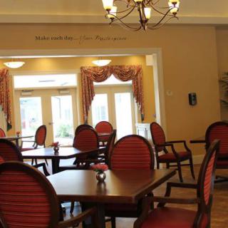 A view of a dining area with red cushioned chairs, tables, and a chandelier.
