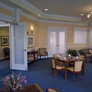 A cozy living room with chairs and tables arranged on a blue carpet.