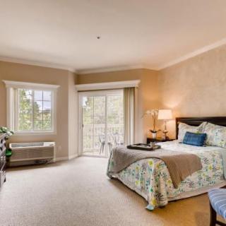 A cozy bedroom with a large bed, soft carpet, and natural light streaming through the window.