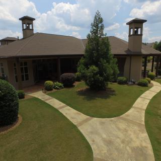 A spacious residential house with a well-maintained lawn and neatly paved pathways.