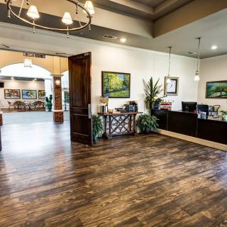 A spacious office reception area with elegant wood flooring, decorative plants, and artwork adorning the walls.