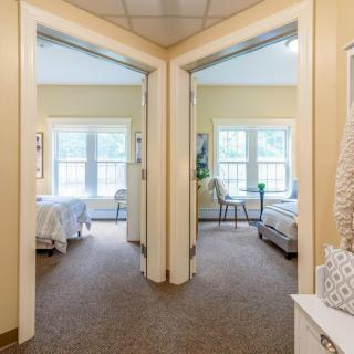 A view of two adjacent bedrooms with large windows and cozy interiors.