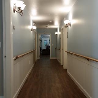 A well-lit indoor hallway with wooden flooring and railings on both sides.