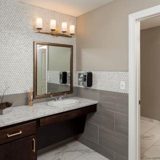 A modern bathroom featuring a stylish vanity with a marble countertop, elegant lighting, and contemporary tile design.