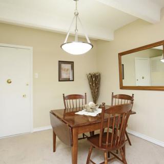 A cozy dining room with a wooden table and chairs, decorated with a wall mirror and artwork.